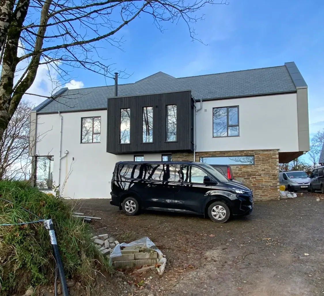 Two-storey home finished in silicone render with dark cladding and stone detailing